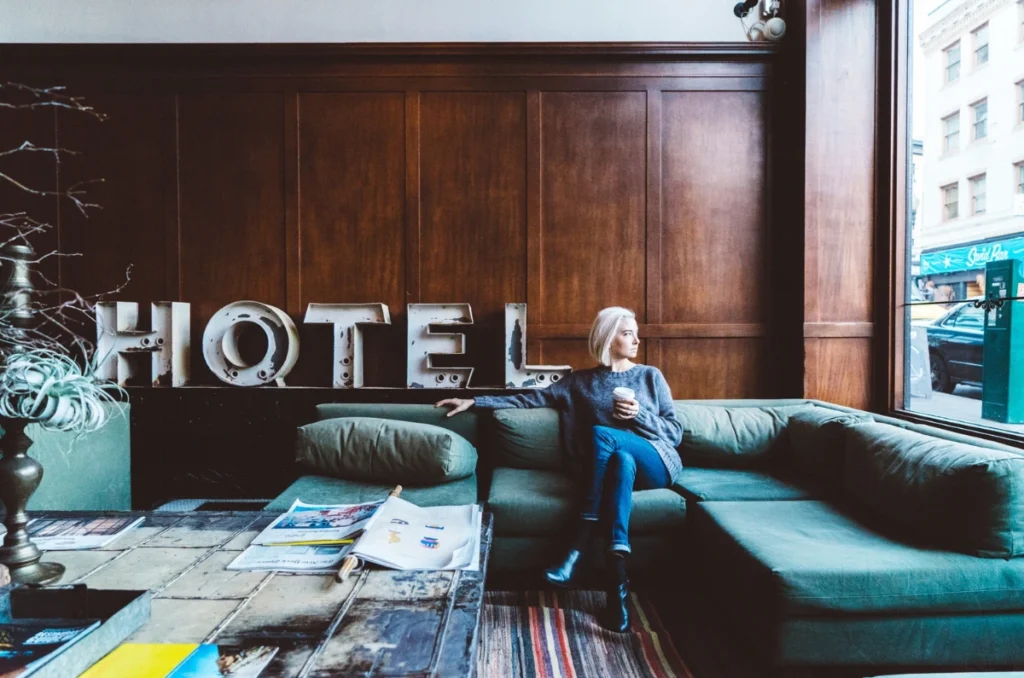 Woman sitting on a green couch in a hotel lobby with large 